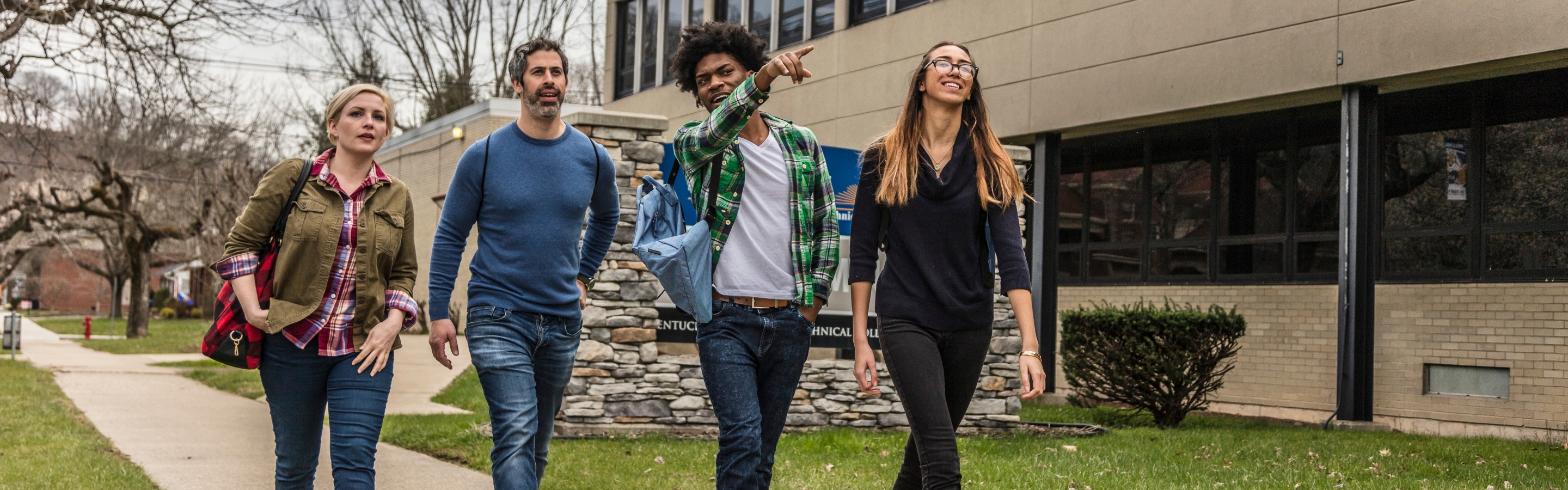 Four students walking together down a pathway in front of a building.